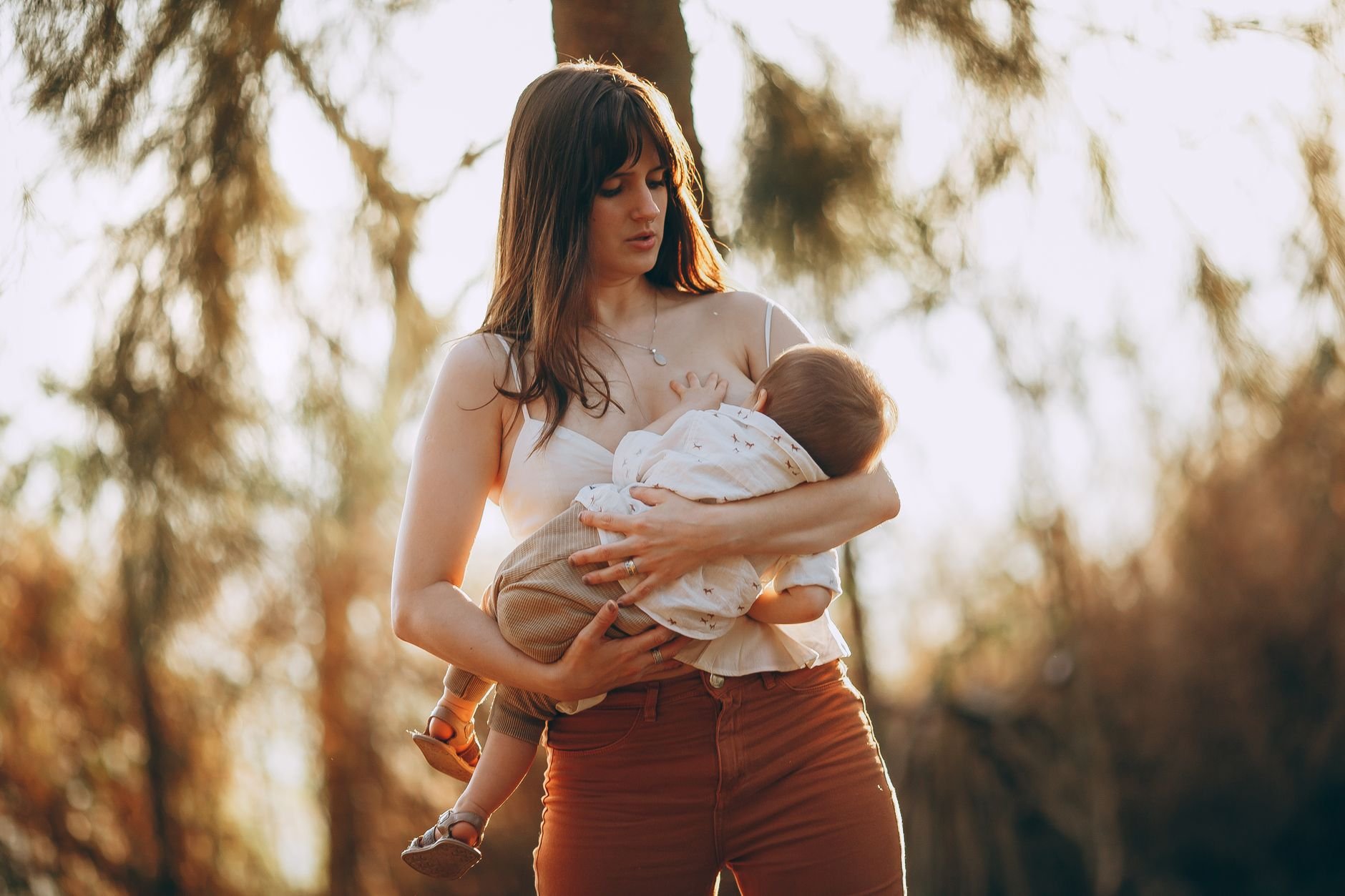 A mother holding her baby during golden hour with soft, warm sunlight